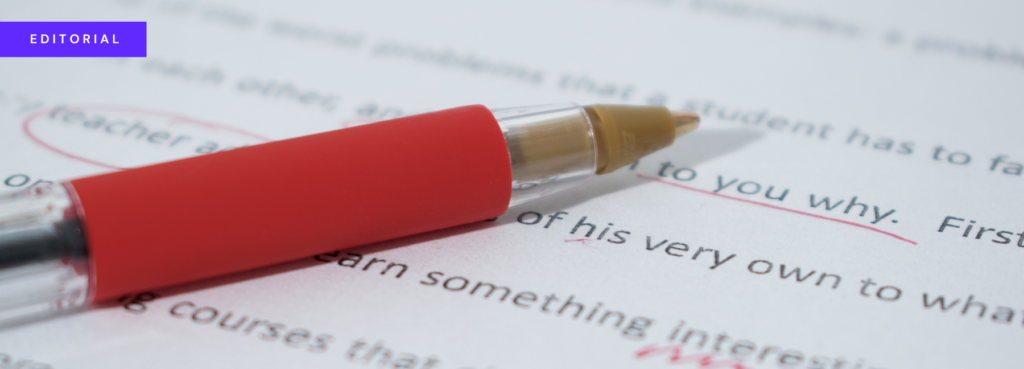 A red biro lying on a piece of paper with typed text on it. Some words have been marked up with the red pen.