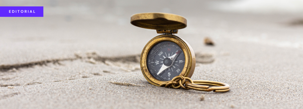 banner showing an old-fashioned brass compass on a sandy surface